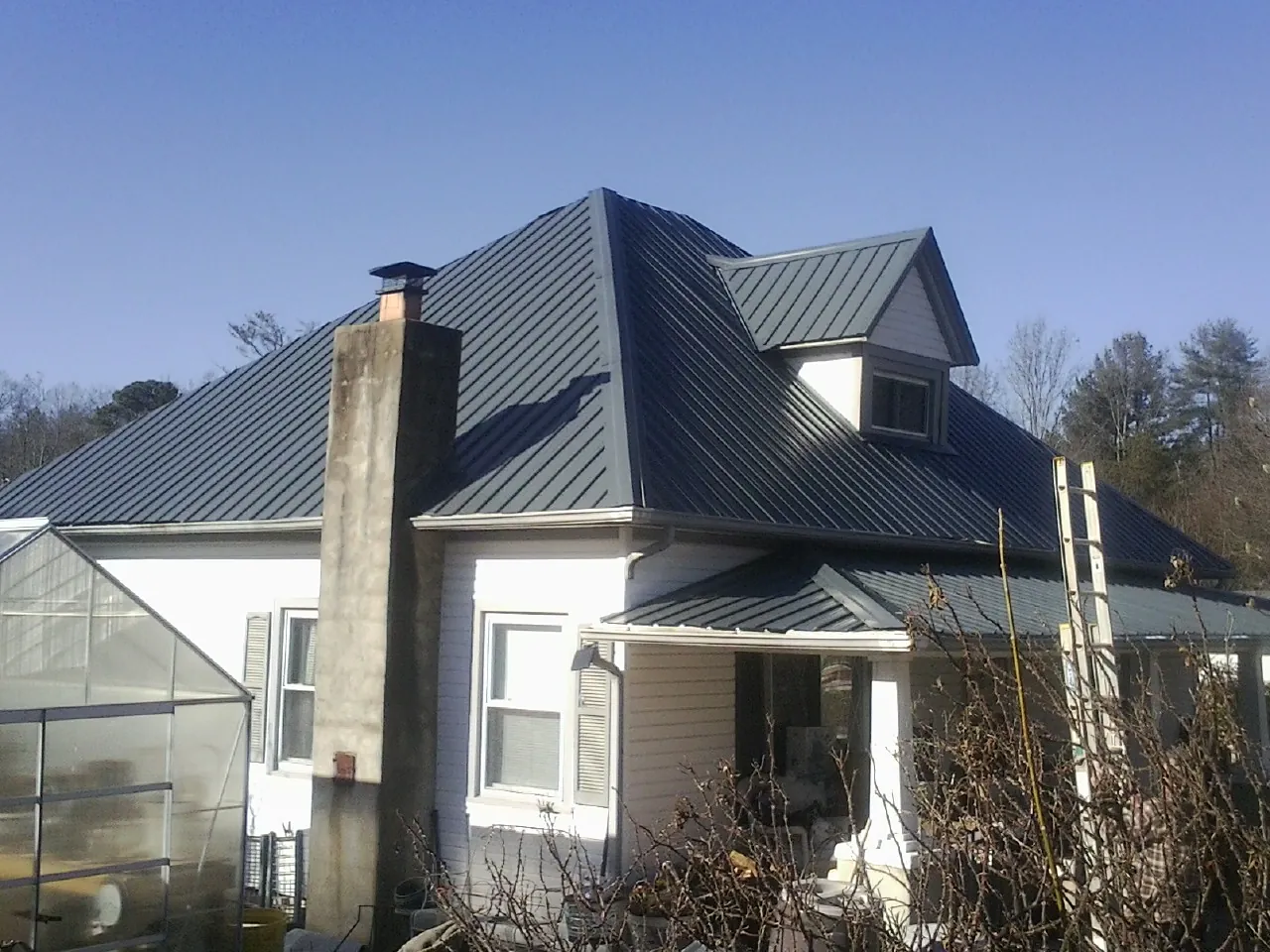 Dark blue standing seam metal roof on a white farmhouse with dormer — Slate & Tile Roof Repair by Roofing Brothers in Willow Grove