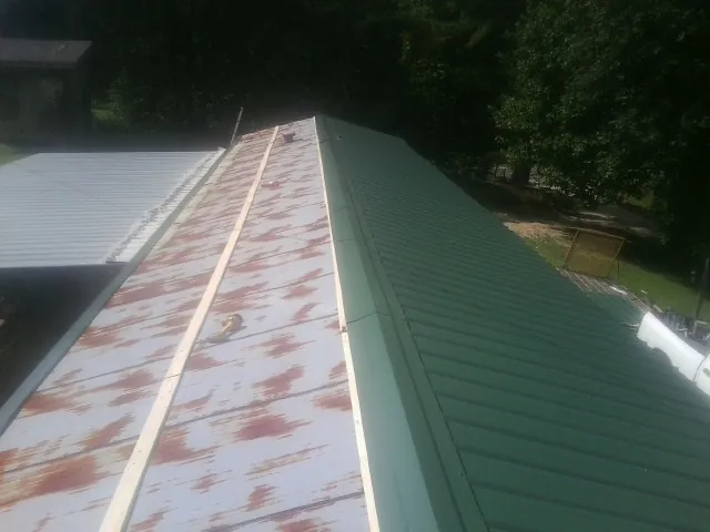 Old rusted panels beside newly installed green metal roofing — Wind Damage Roof Repair by Roofing Brothers in Willow Grove