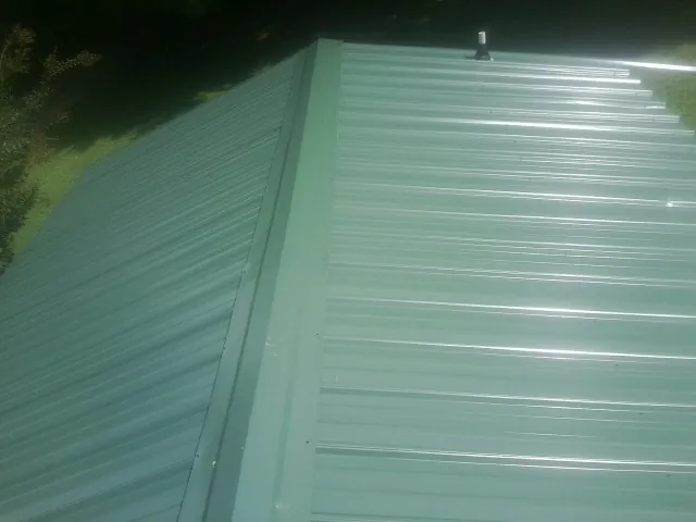 New green metal panels meeting at the ridge of a roof — Flat Roof Repair work by our crew in Willow Grove