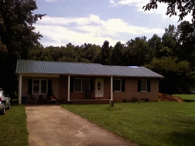 Dark green metal roof on a brick ranch with a covered porch in Willow Grove
