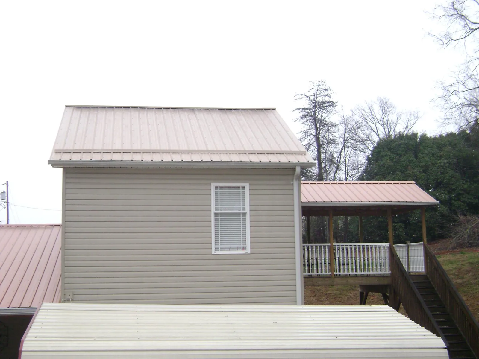 Tan metal roofs on a two story addition and attached porch, from a Roof Replacement job in Willow Grove
