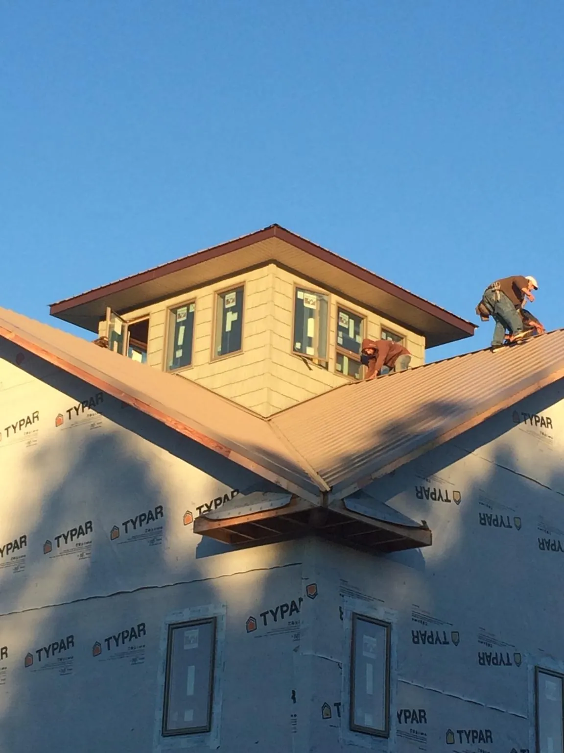Roofers working around a rooftop cupola on a new metal roof at sunset — Roof Waterproofing in Willow Grove by Roofing Brothers